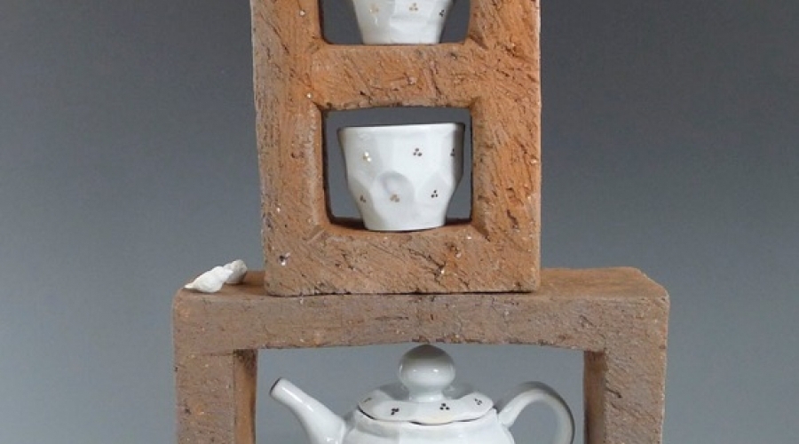 A tea pot and two tea cups sit on top of cinder blocks