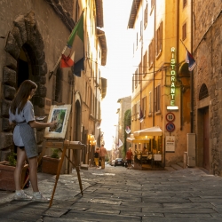 Undergraduate student Sarah Lee paints a city street scene as sunset approaches in downtown Cortona, Italy.