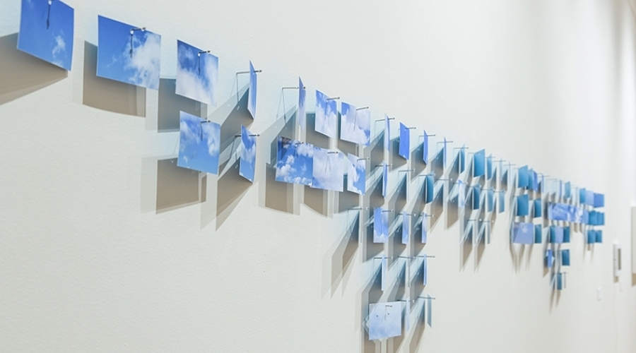 A bunch of different images of a blue sky hang on a wall