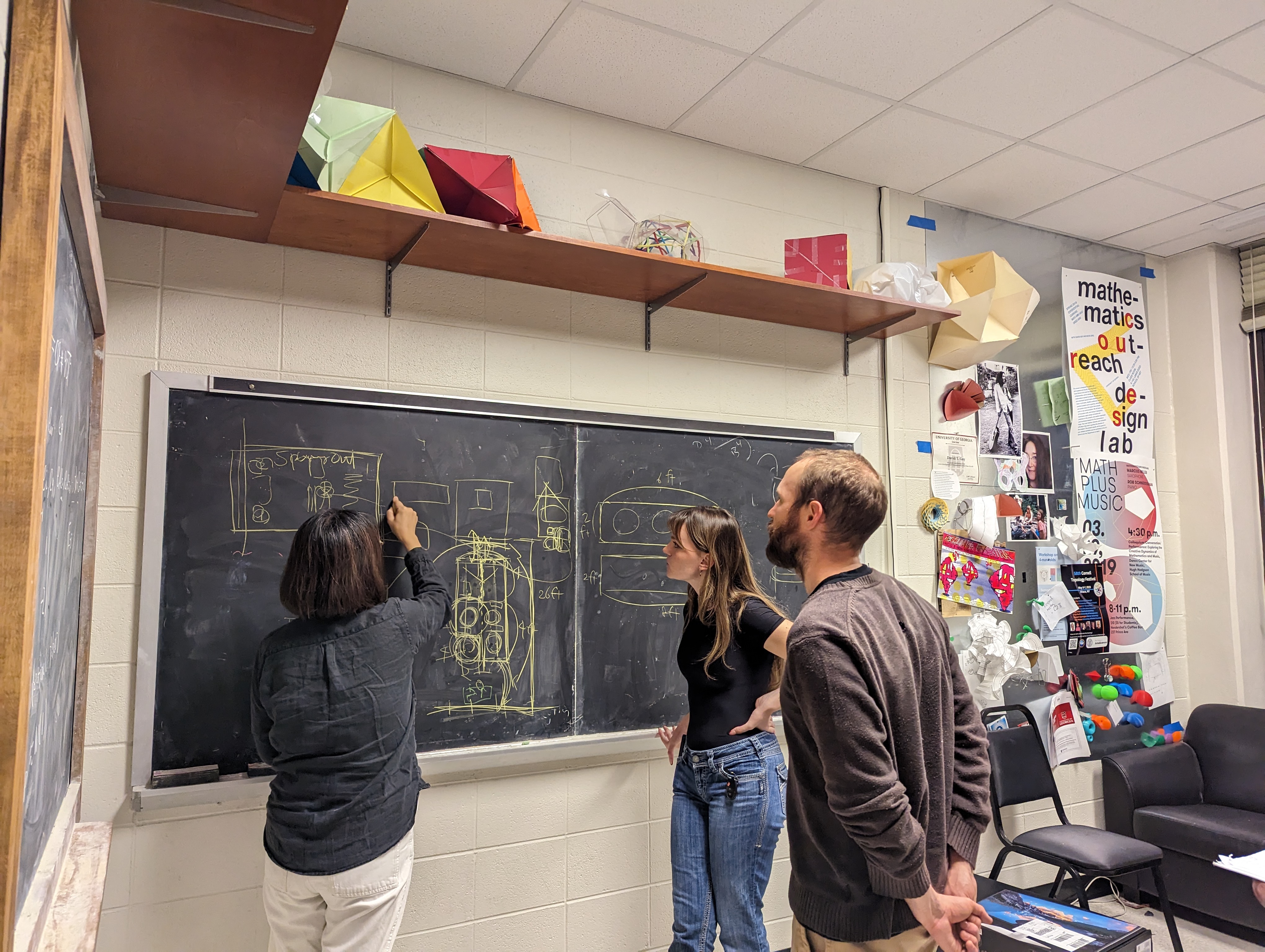 Associate Professor Moon Jang maps out exhibition layout for Spacing Out with graphic design student Charlize Carlisle and mathematics PhD student Alexander Tepper, November 2024. Photo courtesy of Francis Oliver.