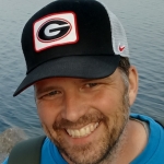 headshot of person smiling with beard and cap with University of Georgia logo.