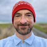 Person with red hat smiling outdoors.