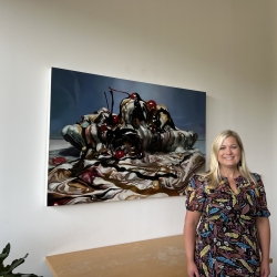 Image of person in front of a painting and desk.