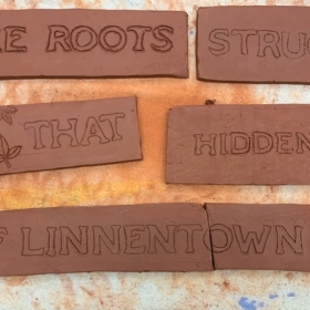Words carved into brick: "The roots struggle that hidden of Linnentown"