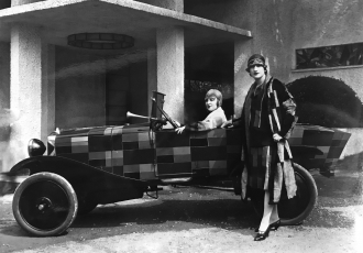 Photograph of two models wearing clothing by Sonia Delaunay, with a Citroën B12 painted after one of the artist’s textile designs, Exposition Internationale des Arts Décoratifs et Industriels, Paris, France, 1925 (photo by Rep Boulogne-Billancourt Photographie).