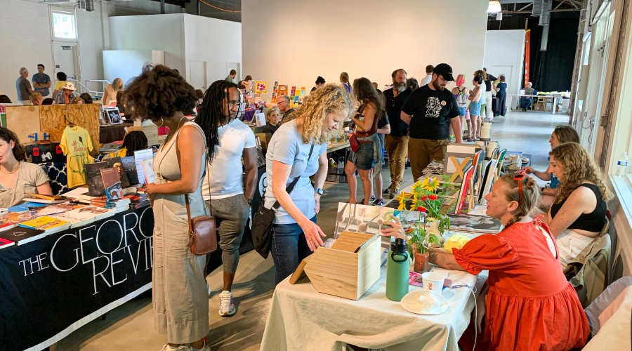 Interior view of the Athenaeum gallery showing Art Book Fair attendees browsing exhibitor tables. Image courtesy of Sidney Chansamone