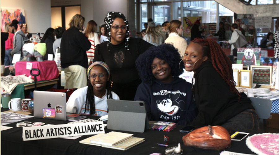 University of Georgia Black Artists Alliance members (L-R) Zahria Cook, Jasmine Best, AJ Aremu and Jordan Campbell pose for a photo behind their joint table at the Dodd market. (Photo/Isabelle Manders)