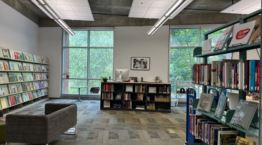 The Art Library as seen from the entrance. The circulation desk is centered, surrounded by two windows. Several shelves displaying books and periodicals are visible.