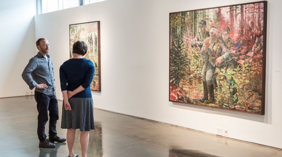 Two people stand in a gallery discussing a piece of art 