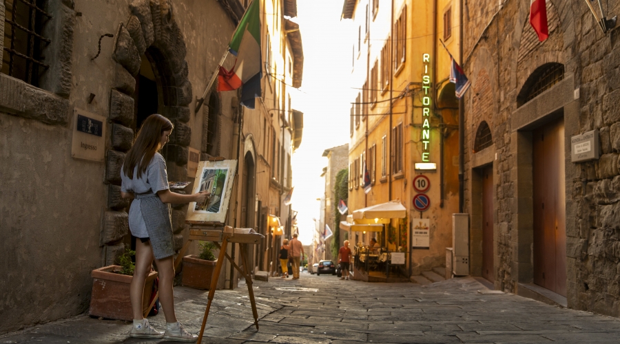 Undergraduate student Sarah Lee paints a city street scene as sunset approaches in downtown Cortona, Italy.