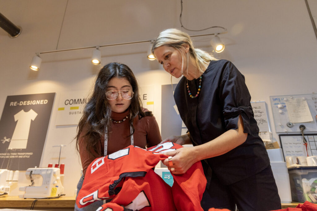(L-R) UGA alumna and Community seamstress Julia Urrea and boutique owner Sanni Baumgaertner discuss repairs needed on a football jersey. 