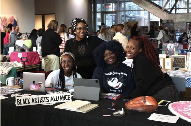University of Georgia Black Artists Alliance members (L-R) Zahria Cook, Jasmine Best, AJ Aremu and Jordan Campbell pose for a photo behind their joint table at the Dodd Market on November 18, 2022.