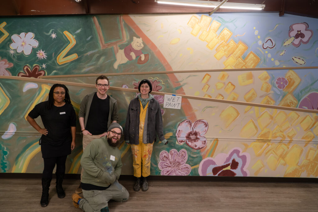 From left to right: Jasmine Best, Jason Rafferty, Caitlin La Dolce, and Hayden Maltese posing in front of the completed interior mural at Bigger Vision of Athens. 