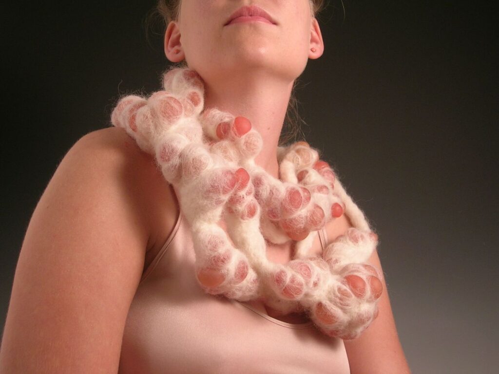 Masako Onodera. Eruption Necklace, 57” x 7”x 4”. Wool, plastic grape, brass.