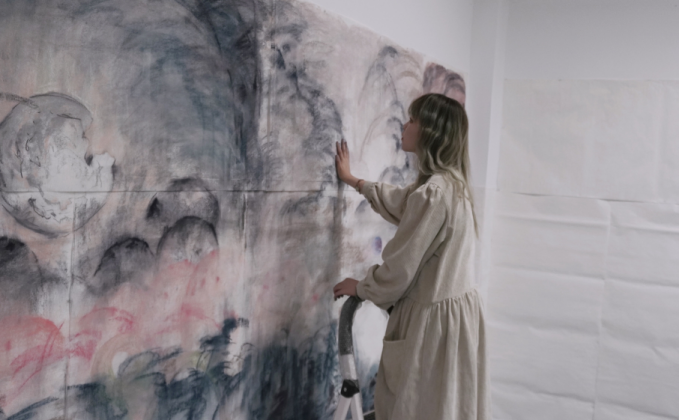 Photo of Yilin standing next to a large drawing